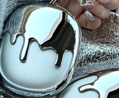 the reflection of a woman's hand holding a silver and black object