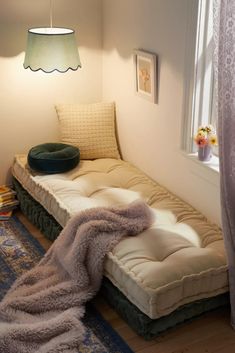 a room with a bed, rug and lamp on the floor in front of a window