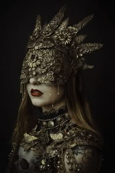 a woman wearing a mask with flowers and chains on her head, in the dark