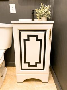 a white toilet sitting in a bathroom next to a plant on top of a cabinet