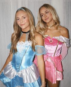 two young women dressed in costumes posing for a photo together, one wearing a blue and pink dress