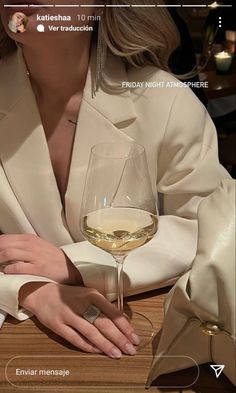 a woman sitting at a table with a glass of wine