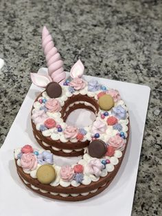 a chocolate cake decorated with flowers and an unicorn horn is on a white square plate