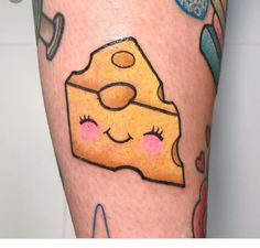 a tattoo with a piece of cheese on it's leg and other items around it