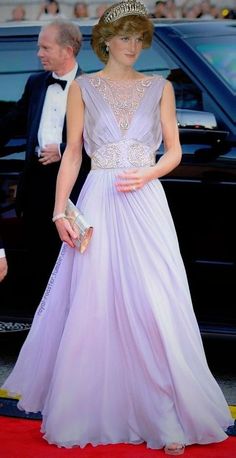 a woman in a purple dress and hat walks down the red carpet