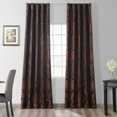 a room with a table, chair and window covered in brown paisley print curtain panels