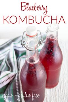 two bottles of blueberry kombucha sitting on top of a white cloth