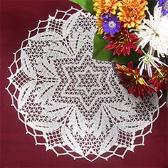 a white doily sitting on top of a table next to a vase filled with flowers