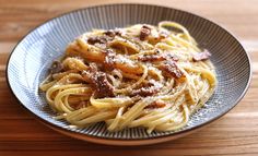 pasta with bacon and parmesan cheese in a bowl on a wooden table top