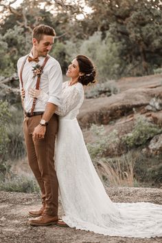 a bride and groom standing together in the woods