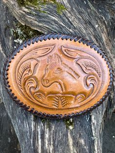 a brown leather belt buckle sitting on top of a tree