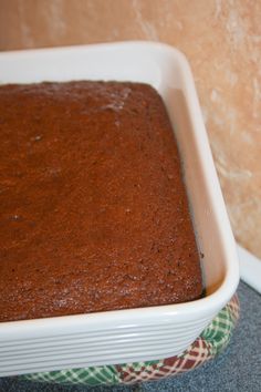 a brown cake in a white dish on a counter