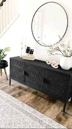 a living room with a large mirror on the wall next to a black sideboard