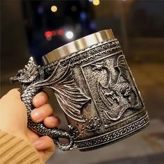 a person holding a dragon mug in their hand