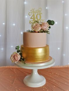 a pink and gold cake with flowers on top