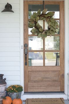 the front door is decorated with pumpkins and greenery