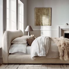 a bed with pillows and blankets on top of it next to a fire place in a room