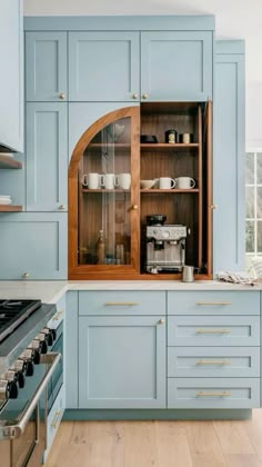 an open cabinet in the middle of a kitchen with blue cupboards and wooden floors