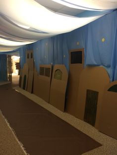 an indoor play area with cardboard castles on the floor and blue drapes hanging from the ceiling