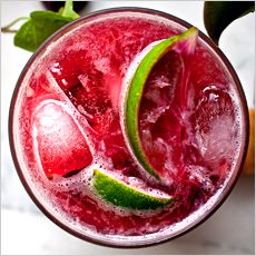 a close up of a drink in a glass on a table with fruit around it