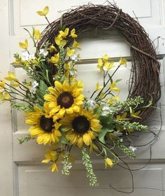 a wreath with sunflowers and greenery on the front door