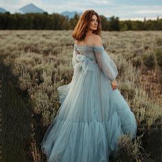 a woman in a blue dress standing in a field