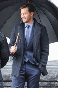 a man in a suit and tie holding an umbrella