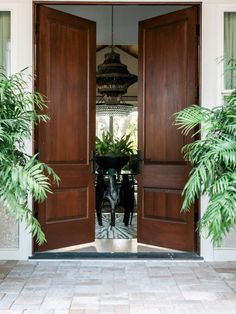 an open door leading to a dining room with potted plants