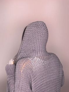 a woman with her back to the camera, wearing a silver knitted hoodie