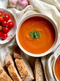 two bowls of tomato soup, bread and tomatoes