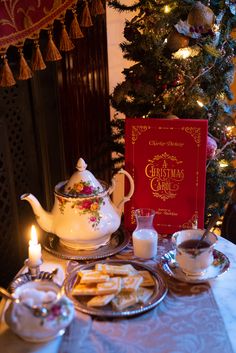 a tea set on a table in front of a christmas tree with cookies and milk