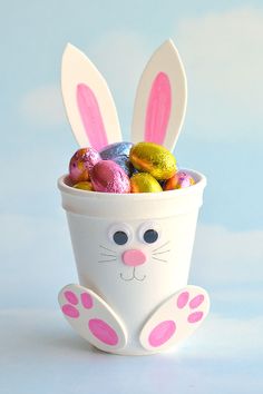 a cup filled with easter eggs and bunny ears