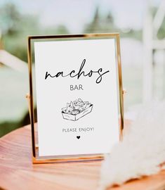 a sign that says nachos bar on top of a wooden table next to a white feather