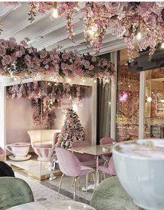 the interior of a restaurant with pink flowers on the ceiling and tables in front of it