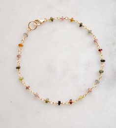 Spread creativity and joy with this multicolor gemstone Tourmaline bracelet! This handmade beauty features natural Tourmaline crystals in a variety of hues, including pink, black, green, and yellow. Each bracelet is unique, with no set pattern, making each one a one-of-a-kind. It comes in your choice of sterling silver or 14k gold filled. Tourmaline Meaning: The birthstone for October, Tourmaline is believed to promote inspiration, boost confidence, and combat fear. Stone Size: Average 3-4mm Mat Gold Bracelets With Natural Stones And Tourmaline, Gold Tourmaline Bracelets With Natural Stones, Dainty Multicolor Gemstone Bracelet, Dainty Multicolor Gemstone Beads Bracelets, Spiritual Multicolor Tourmaline Beaded Bracelets, Elegant Multicolor Tourmaline Beaded Bracelets, Tourmaline Meaning, Beauty Features, Boost Confidence