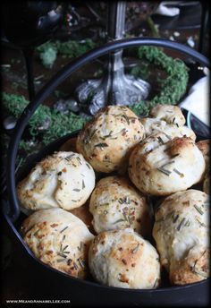 a bowl filled with rolls covered in cheese and herbs