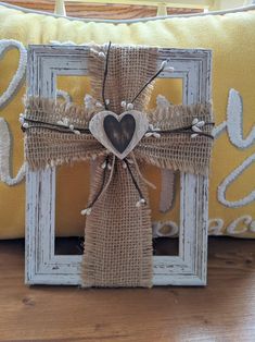 a cross made out of burlock with a heart hanging from the front on a pillow