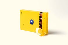 an open yellow box with chocolates in it on a white surface, next to a banana peel