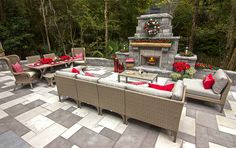 an outdoor fireplace and seating area with red pillows on the couches next to it