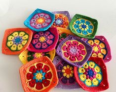 colorful crocheted dishcloths are arranged on a white surface