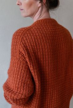 a woman in an orange sweater is looking off to the side