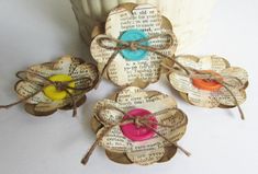 four pieces of art made out of old book pages with colorful buttons and twine