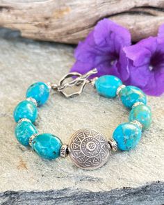 This classic Boho style Turquoise bracelet features amazing Sky blue Turquoise nuggets from the Kingman Mine in AZ. A large round Hilltribe Silver Sun charm is the focal. Each Turquoise nugget is separated by a small fine Silver Hilltribe bead. A Tribal fine silver Toggle is the closure. This Turquoise is so beautiful! Wear alone or stack with your other faves. Rustic Blue Adjustable Beaded Bracelets, Rustic Blue Adjustable Beaded Bracelet, Rustic Adjustable Blue Beaded Bracelet, Rustic Handmade Blue Beaded Bracelets, Bohemian Turquoise Beaded Nickel Free Bracelets, Bohemian Turquoise Beaded Bracelets Nickel Free, Bohemian Turquoise Beaded Nickel-free Bracelets, Nickel-free Turquoise Beaded Bracelets For Festivals, Rustic Turquoise Bracelet Jewelry