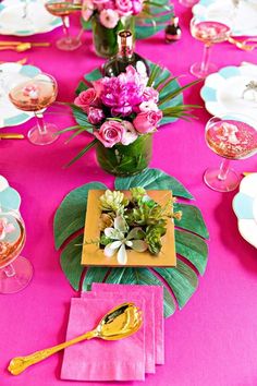 the table is set with pink flowers and gold utensils for dinner party guests