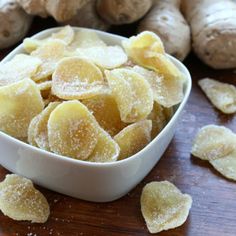 sliced ginger in a white bowl next to fresh ginger