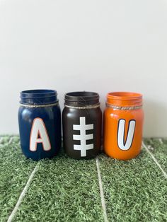 three painted mason jars sitting on top of a green carpet