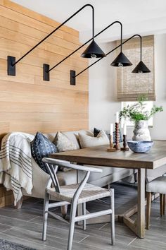 a living room and dining area with wood paneling on the wall, white couches and chairs