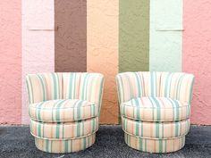 two striped chairs sitting next to each other in front of a wall with multicolored stripes