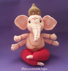 a crocheted stuffed elephant sitting on top of a red ball with a gold crown on it's head