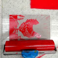 a roll of red paper sitting on top of a piece of blue plastic next to a red object